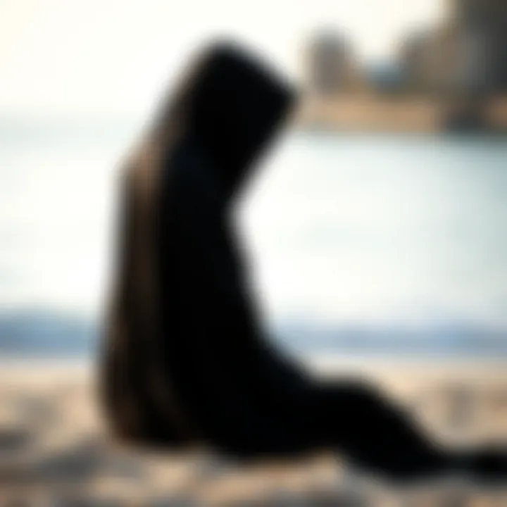 Stylish black hooded poncho draped on a beach