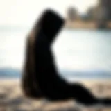 Elegant Black Hooded Poncho at the Beach Stylish black hooded poncho draped on a beach