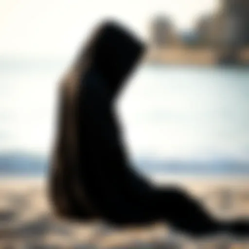 Elegant Black Hooded Poncho at the Beach Stylish black hooded poncho draped on a beach